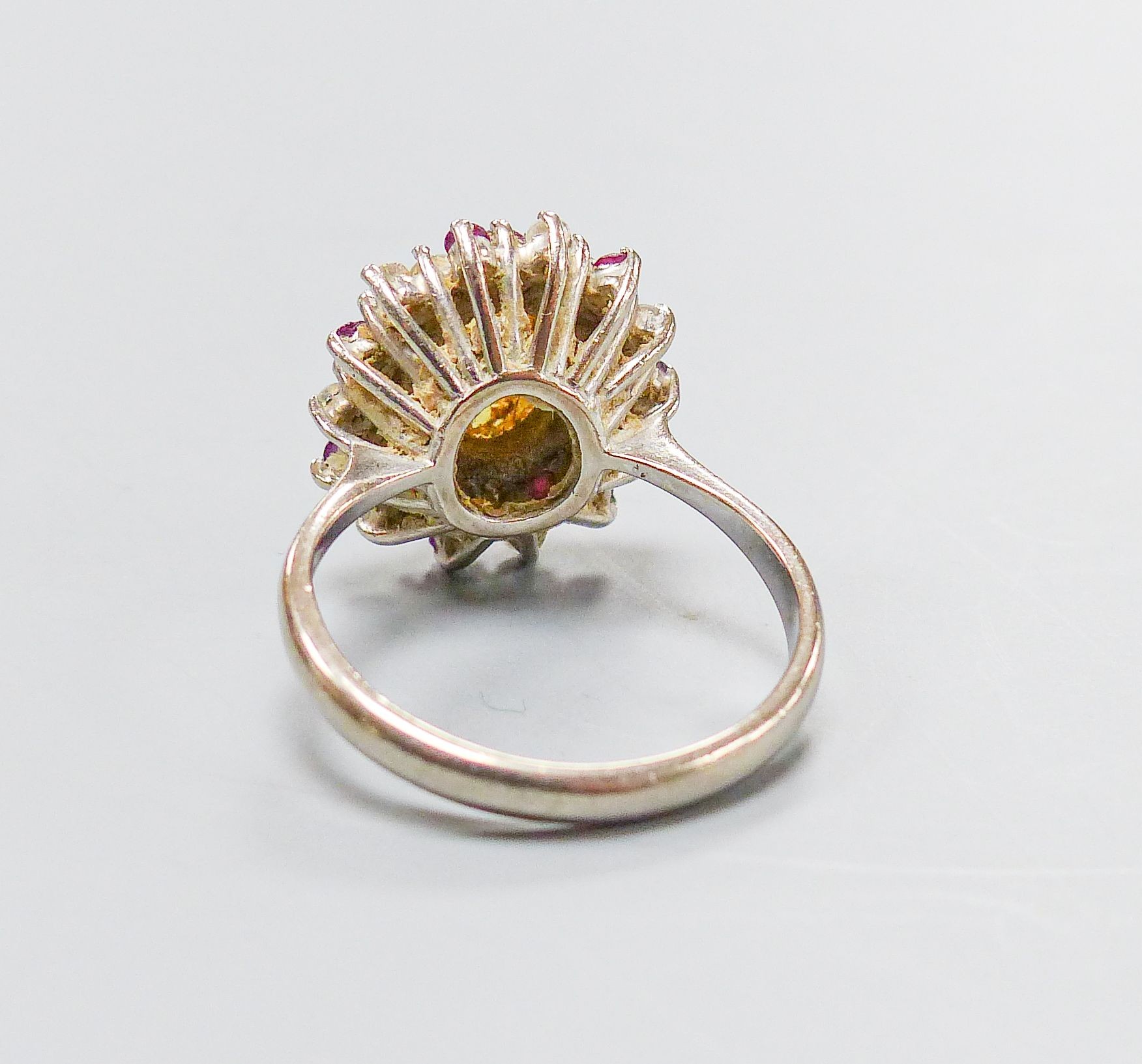 An 18ct white metal, white opal, ruby and diamond set oval cluster ring, size N, gross weight 6.1 grams.